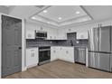 Modern kitchen with white cabinets, stainless steel appliances, and gray backsplash at 3553 Greenfield Ave, Orlando, FL 32808