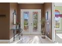 Elegant entryway with double doors, tile flooring, and a glass-top console table at 1215 Johns Cove Ln, Oakland, FL 34787