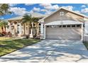 Tan house with palm trees, two-car garage, and grassy lawn at 1965 Fairway Loop, Kissimmee, FL 34746