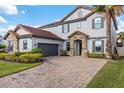 Two-story home with a gray facade, tile roof, and a paved driveway at 12023 Gold Creek Trl, Windermere, FL 34786