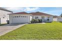 Front view of a single-story house with a garage and grassy yard at 610 Crane Dr, Poinciana, FL 34759