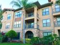 Exterior view of a Mediterranean-style apartment building with palm trees and landscaping at 904 Charo Pkwy # 536, Davenport, FL 33897