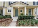 Front entrance of two story townhome with teal door and well maintained landscaping at 7321 Brightland St, Windermere, FL 34786