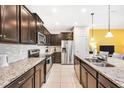 Modern kitchen with dark wood cabinets, granite countertops, and stainless steel appliances at 8921 Sydney Ave, Kissimmee, FL 34747