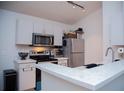 Compact kitchen with white cabinets, stainless steel appliances, and light countertops at 940 Village Trl # 9-303, Port Orange, FL 32127