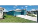 Front view of a teal house with a two-car garage and landscaping at 1963 Turtle Dove Ln, Kissimmee, FL 34746