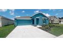 Two-car garage teal house with a landscaped front yard at 1963 Turtle Dove Ln, Kissimmee, FL 34746