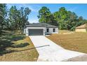 New construction home showcasing a gray garage door and a long driveway at 16921 Sw 25Th Ct, Ocala, FL 34473