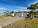 Single-story house with a three-car garage, paver driveway, and palm trees at 402 Blue Lake Cir, Kissimmee, FL 34758