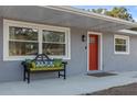 Inviting front porch with a red door and a bench, showcasing curb appeal at 27623 Lisa Dr, Tavares, FL 32778