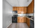 Galley style kitchen with wood cabinets, black appliances, and tile flooring at 3954 Versailles Dr # 3954B, Orlando, FL 32808