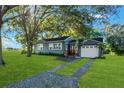 Gray house with a white garage, red door and nicely landscaped lawn at 20 Maynard Ave, Orlando, FL 32803