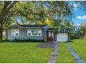 Gray house with a white garage, red door and nicely landscaped lawn at 20 Maynard Ave, Orlando, FL 32803