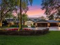 Luxury waterfront home exterior at sunset with lush landscaping and a three-car garage at 100 Blue Lake Ct, Longwood, FL 32779