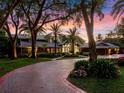 Paver driveway leading to a beautiful home at sunset, surrounded by trees and landscaping at 100 Blue Lake Ct, Longwood, FL 32779