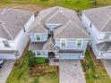 An aerial view showcasing a two-story house with gray tile roofing and a paved driveway at 1670 Moon Valley Dr, Davenport, FL 33896
