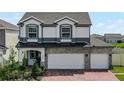 Two-story house featuring a gray and white exterior, three-car garage, and a brick driveway at 7670 Modica St, Clermont, FL 34714