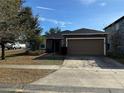 Front view of a one-story house with a brown exterior, attached garage, and landscaping at 146 Prairie Falcon Dr, Groveland, FL 34736