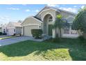 Green house with palm trees, two-car garage, and a manicured lawn at 422 Troon Cir, Davenport, FL 33897