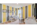 Bedroom with yellow and gray striped walls, crib, changing table, and toddler table at 1300 Hanoverian Dr, Lake Alfred, FL 33850