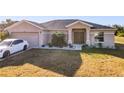 Tan house with gray roof, double door entry, and a white car in driveway at 1218 Coda Ct, Dundee, FL 33838