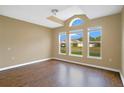 Empty living room with wood-look flooring, large windows, and neutral walls at 2410 Hatton Chase Ln, Kissimmee, FL 34746