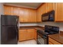 Kitchen with wood cabinets, granite countertops, and black appliances at 3262 Villa Strada Way, Orlando, FL 32835