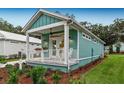 Side view of teal cottage showcasing landscaping and lawn at 12133 Grand Oak Ln, Oxford, FL 34484