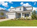 Two-story house with gray siding, two-car garage, and landscaped yard at 381 Citrine Loop, Kissimmee, FL 34758