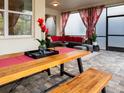 Covered patio with wooden table, seating area, and red curtains at 8933 Amelia Downs Trl, Kissimmee, FL 34747