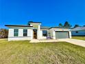 Single-story home with gray garage door and a well-manicured lawn at 14949 Sw 65Th Avenue Rd, Ocala, FL 34473