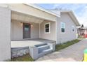 Covered front porch with concrete floor, front door, and light fixtures at 550 N Ridgewood Ave, Daytona Beach, FL 32114