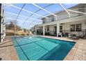 Screened-in pool with lounge chairs and patio furniture at 1528 Mulligan Blvd, Davenport, FL 33896