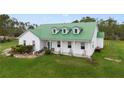 Inviting farmhouse with green metal roof, white siding, and landscaped yard at 3520 Hyder Ave, Deltona, FL 32738