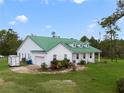 Farmhouse exterior with green metal roof, white siding, and attached garage at 3520 Hyder Ave, Deltona, FL 32738