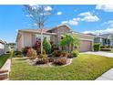 Landscaped front yard with tropical plants and brick driveway at 440 Alcove Dr, Groveland, FL 34736