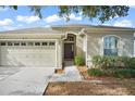 Front exterior of a one-story home with a two-car garage, driveway, walkway, and landscaping at 10421 Andover Point Cir, Orlando, FL 32825