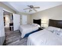 Two beds in a bedroom with ceiling fan, wood-look tile, and open doorway at 3100 Parkway Blvd # 110, Kissimmee, FL 34747