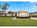 Single-story home with a lush green lawn and palm trees under a blue sky at 715 Sanctuary Dr, Oviedo, FL 32766