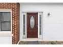 Close-up of a brown wooden front door with an oval window and brick accents at 1413 Dorothy Ave, Haines City, FL 33844