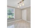 Empty room with tiled flooring, window, closet, and a unique light fixture at 6030 Village Cir, Orlando, FL 32822