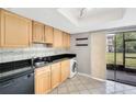 Compact kitchen with black countertops, light wood cabinetry, and black appliances at 6030 Village Cir, Orlando, FL 32822