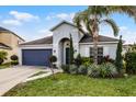 Inviting one-story home with navy blue garage, palm tree, and landscaped yard at 2213 Grantham Ave, Davenport, FL 33837