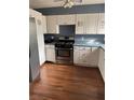 Kitchen with white cabinets, stainless steel appliances, and laminate flooring at 2680 Palmetto Rd, Mount Dora, FL 32757