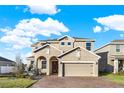 Tan two-story house with a three-car garage and landscaping at 488 Sapphire Dr, Davenport, FL 33837