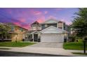 Two-story house with gray siding, a large garage, and a landscaped yard at 2377 Victoria Dr, Davenport, FL 33837