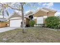 Tan house with white garage door and lush landscaping at 1314 Megan Way, Apopka, FL 32703