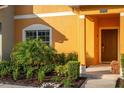 Townhome's front entrance with orange stucco, landscaping, and a brown door at 8931 Bismarck Palm Rd, Kissimmee, FL 34747