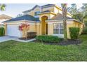 Two-story house, tan exterior, white garage door, landscaping, palm trees at 8458 Secret Key Cove, Kissimmee, FL 34747