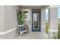 Inviting front porch with a blue door, a chair, and potted plant at 218 Amberwood Way, Umatilla, FL 32784
